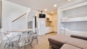 Une petite cuisine moderne et fonctionnelle, équipée d’un four à micro-ondes, d’une cuisinière et d’un évier. Un coin repas avec une table et des chaises est à disposition, ainsi qu’un lit superposé avec un matelas.