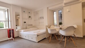 Une chambre moderne comprenant un lit, des tables de chevet, une petite table avec des chaises et des étagères intégrées.