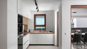 A modern kitchen with white cabinets, a wooden countertop, and a window above the sink. - 5-Star Seaview: 2-Bed Apt with Pool (Vir)