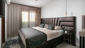 A modern bedroom with a large bed, a bedside table, and a hanging light fixture. - 5-Star Seaview: 2-Bed Apt with Pool (Vir)
