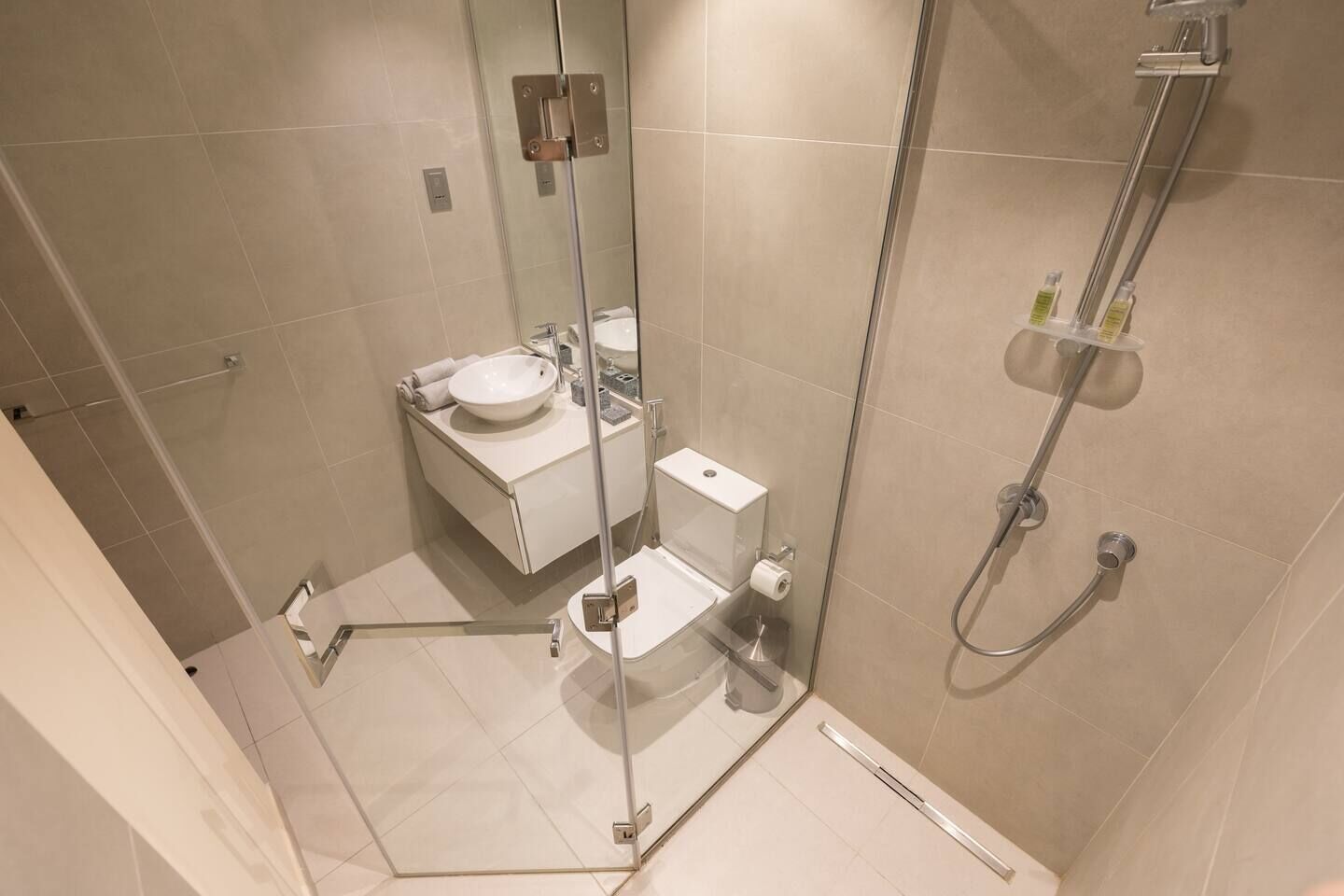Ein modernes Badezimmer mit einer Duschkabine, einem weißen Waschbecken und einer Toilette.