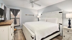 A bedroom with a white bed, a ceiling fan, a dresser, and a nightstand. - Escape to paradise! 1BR Beachfront Condo in Destin (Destin)