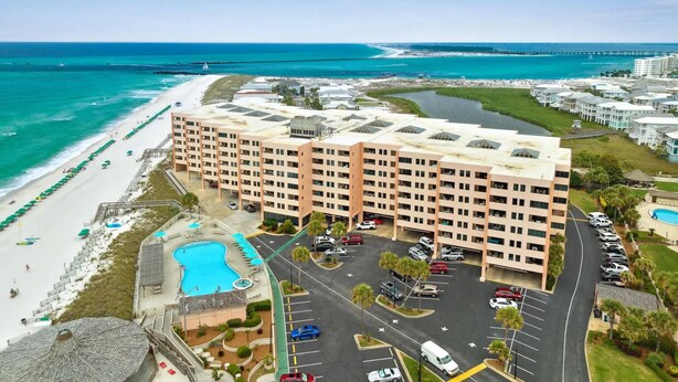 A beachfront hotel with multiple floors, a swimming pool, and a parking lot. - Escape to paradise! 1BR Beachfront Condo in Destin (Destin)