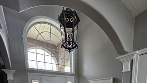 A hallway with a wooden floor, a gray rug, a bench, a large window, and a decorative ceiling light. - Avon Lake, Avon golf course home, 1,000 s.f. open outdoor deck on course lake (Avon)