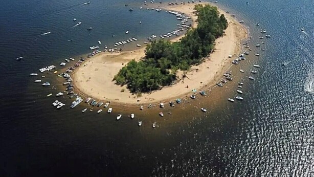 Vista aérea de una isla circular con una playa y barcos.