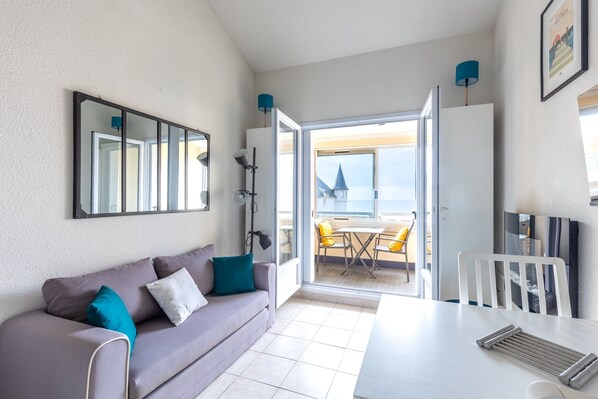 Une chambre moderne équipée d’un canapé, d’une table à manger, d’un téléviseur et d’une grande fenêtre donnant sur la mer.