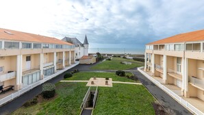 A hotel with a central courtyard, balconies, and a view of the sea.