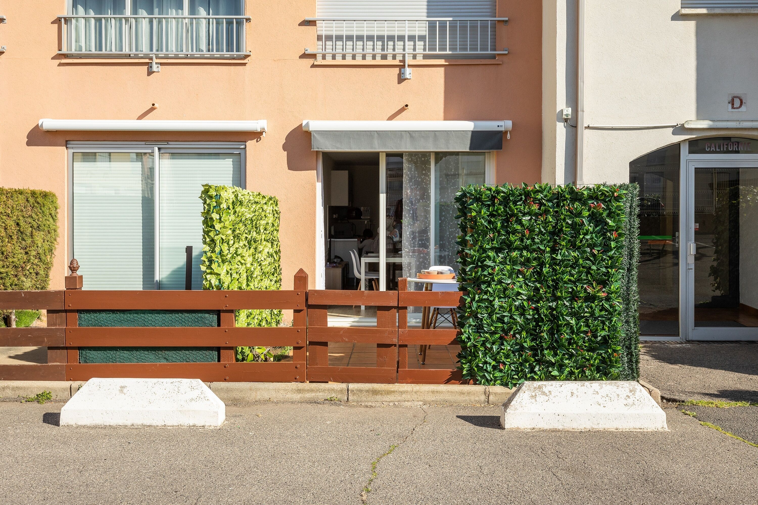A residential building with a gated entrance, a visible balcony, and a door labeled 'CALIFORNIA'.