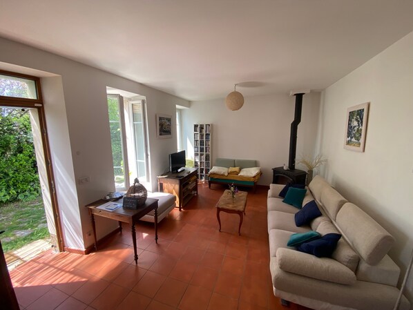 Una sala de estar con sofá, mesa de centro, televisor, estantería y chimenea.