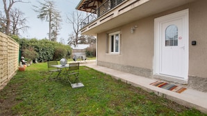 A house with a balcony, a front door, and a small garden area with a table and chairs.