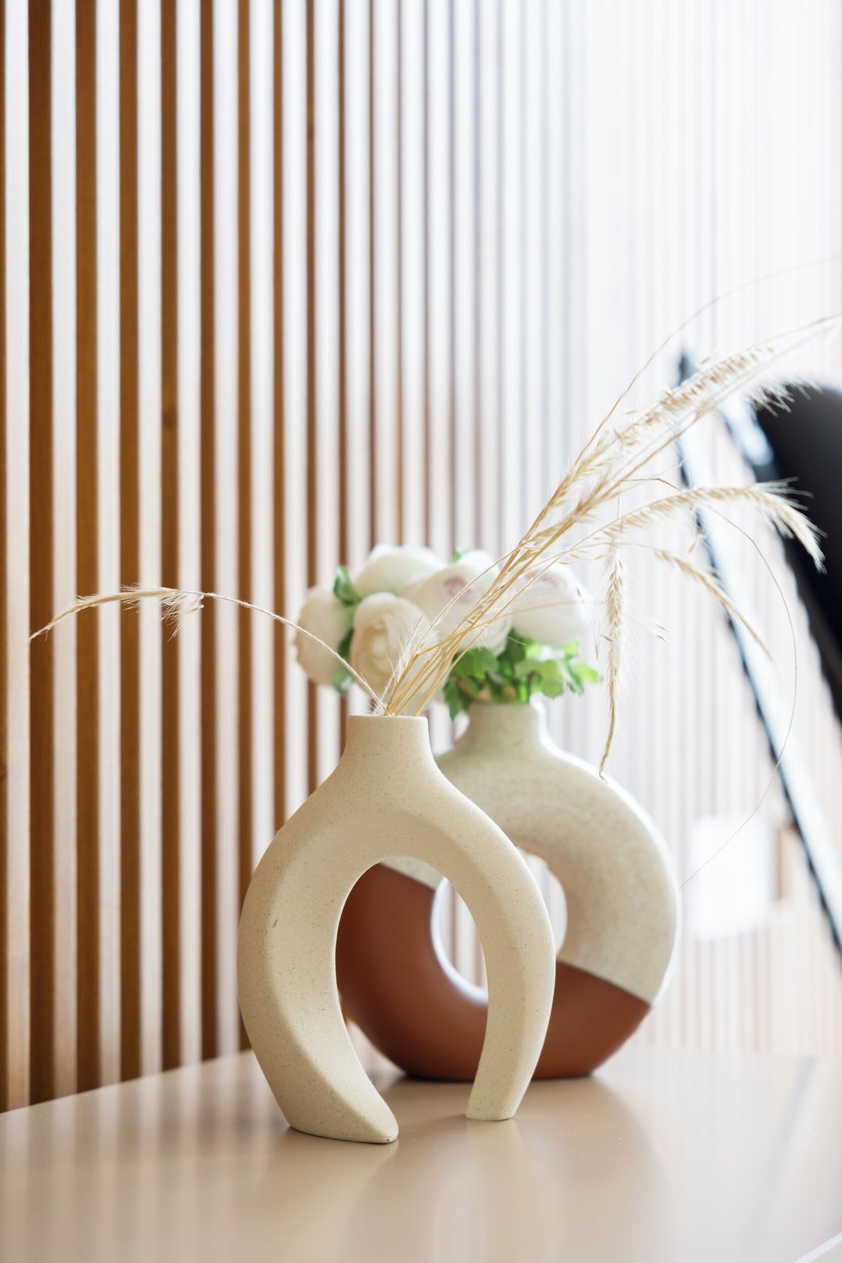 Two ceramic vases with a rustic design, placed on a table against a striped background.