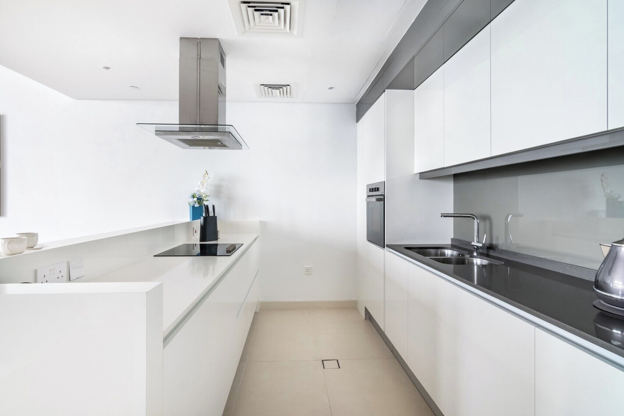 Een moderne keuken met witte kasten, roestvrijstalen apparatuur en een zwart aanrecht.