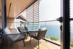 A balcony with wicker chairs and a table, overlooking a city and the sea. - Sea View 2BR Bluewaters (Dubai)
