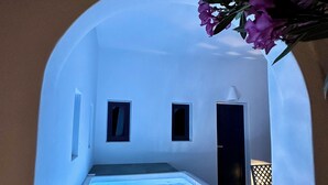 Et moderne spa-område med en stor, klar pool, et lille vindue og en dør til et andet rum.