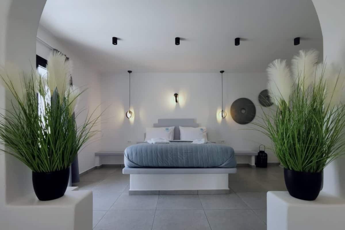 Quarto moderno com uma cama grande, mesas de cabeceira e plantas em vasos.