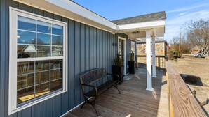 A covered porch with a bench, a stone wall, and a flag. - BLUEBERRY COTTAGE is located in Mena.  WIFI, remodeled , Lockable bike storage ! (Mena)