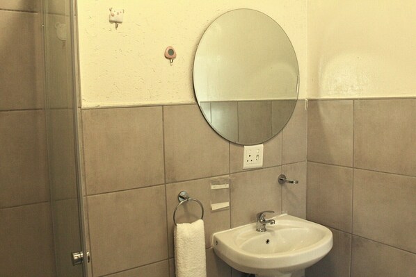 Une salle de bain avec un miroir rond, un lavabo et un porte-serviettes.