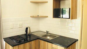 A kitchen with a black countertop, wooden cabinets, a stainless steel sink, and a built-in oven. - Charming 1-bed Apartment in Sandton (Johannesburg)
