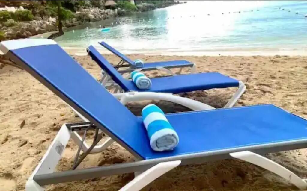 Een strand met blauwe ligstoelen en een blauwe handdoek.