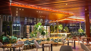 A modern restaurant with a view of the city at night, featuring a mix of seating arrangements and a warm, illuminated ceiling. - The Address Dubai Marina 1BR (Dubai)