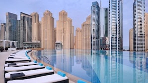 A poolside area with lounge chairs and a clear view of high-rise buildings in the background. - The Address Dubai Marina 1BR (Dubai)