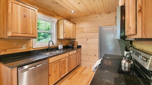 Eine kleine Küche mit Holzschränken, einem Edelstahl-Geschirrspüler, einem Kühlschrank und einem Herd.