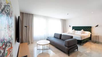 Une chambre d’hôtel moderne, dotée d’un grand lit, d’un canapé, d’une petite table et d’un téléviseur à écran plat.