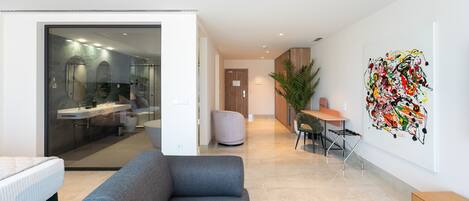 A modern living room with a grey sofa, a small table, and a wall-mounted abstract painting.