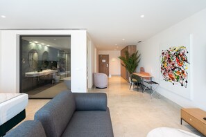 A modern living room with a grey sofa, a small table, and a wall-mounted abstract painting. - Hotel ASA La Marina by SH Hoteles  (Ondara)