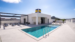 Zona de piscina al terrat amb gandules, una piscina i un edifici amb el rètol 'ASA'.