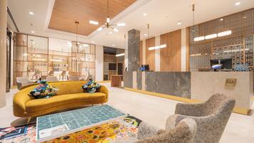 A modern lobby with a yellow sofa, a patterned coffee table, and a reception desk.
