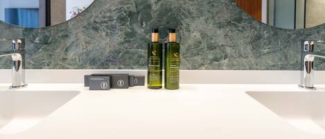 A bathroom with two sinks, a large mirror, and two bottles of skincare products.