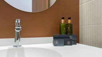 A bathroom with a white sink, a chrome faucet, and toiletries on the counter.