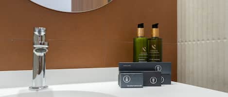 Ein Badezimmer mit einem weißen Waschbecken, einem Chrom-Wasserhahn und Pflegeprodukten auf der Ablagefläche.