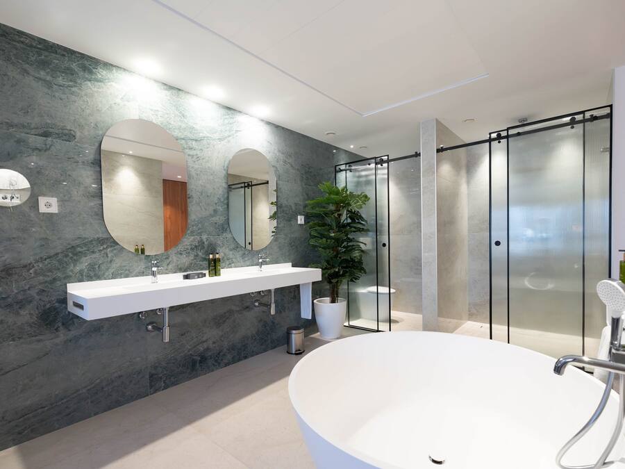 Een moderne badkamer met een groot ovaal bad, een witte wastafel met twee spiegels en een douchecabine van glas.