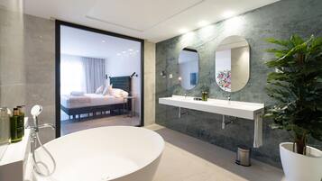 Une salle de bain moderne avec une baignoire sur pieds, un grand miroir et un lavabo blanc.