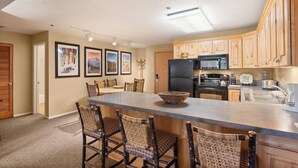 A spacious kitchen with a large island, wooden cabinets, and a refrigerator. - North Of Nell, Unit 2k (Aspen)