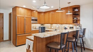 A kitchen with wooden cabinets, a granite countertop, a built-in oven, and a bar area with stools. - North Of Nell, Unit 2m (Aspen)