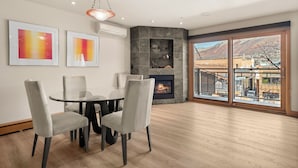A dining area with a fireplace, large windows, and a view of a mountainous landscape. - North Of Nell, Unit 3j (Aspen)