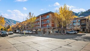 A hotel with a ground floor restaurant, multiple balconies, and a view of mountains. - North Of Nell, Unit 3j (Aspen)