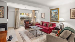 A living room with a red sofa, a grey sofa, a coffee table, a lamp, and a painting on the wall.