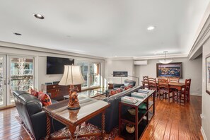 A spacious living room with a leather sofa, a glass coffee table, and a dining area with wooden chairs and a table. - North Of Nell, Unit 4e (Aspen)