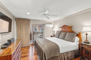 A hotel room with a bed, a desk, a chair, a ceiling fan, a window with curtains, and a view of the outside. - North Of Nell, Unit 4e (Aspen)