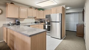 A modern kitchen with wooden cabinets, a granite countertop, stainless steel appliances, and a built-in oven.