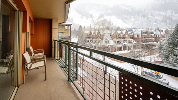 A balcony with a view of a snowy town and mountains.