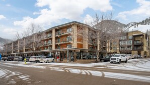 A multi-story hotel with a central atrium, outdoor seating area, and a parking lot with several cars.