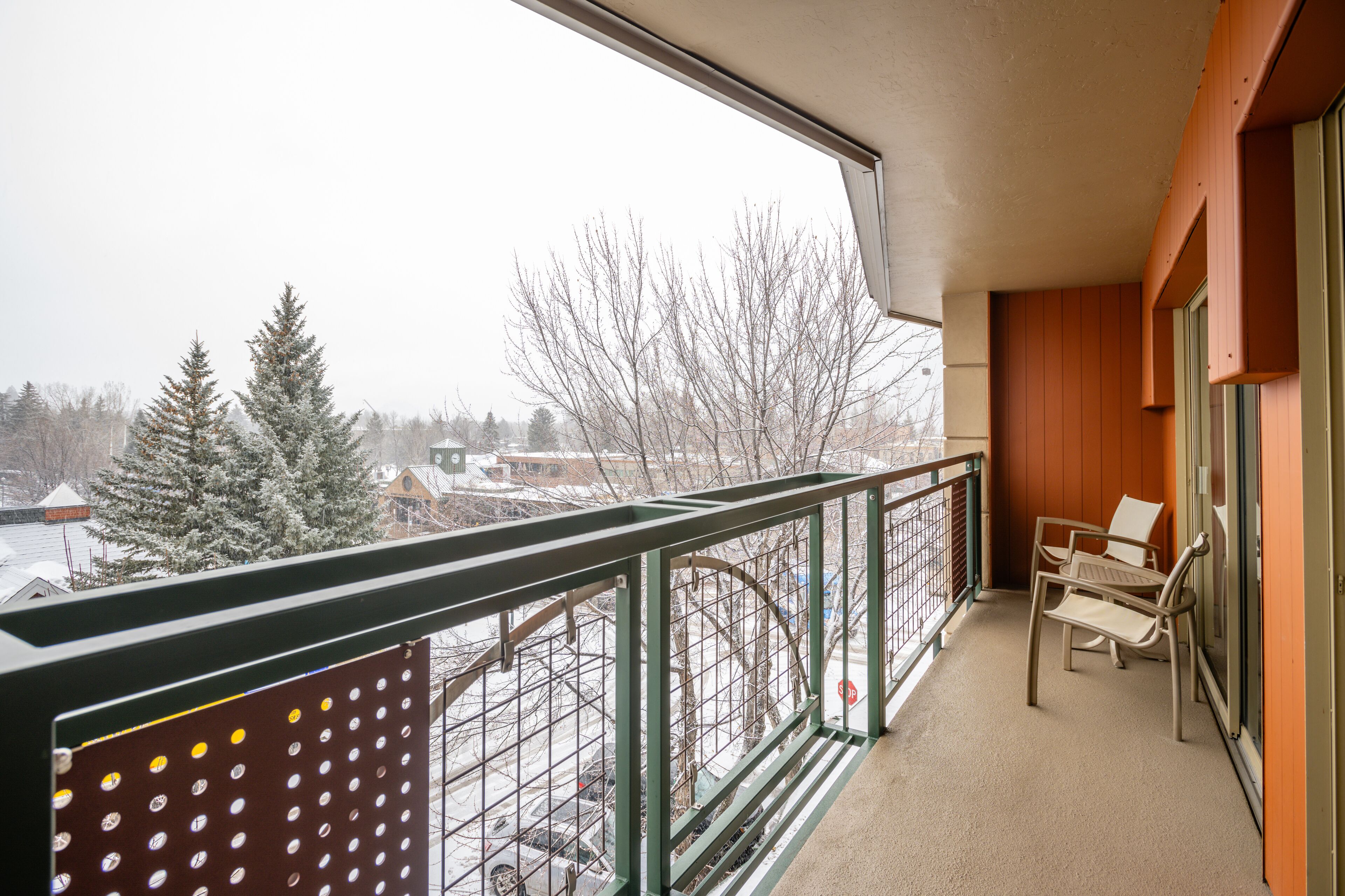 Ein Balkon mit Blick auf verschneite Bäume und ein entferntes Gebäude.