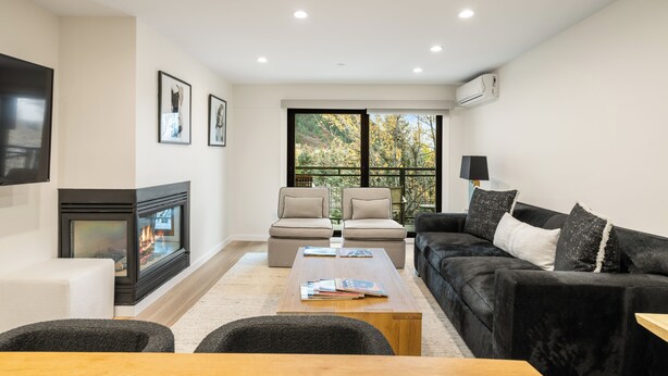 A modern living room with a fireplace, two sofas, a coffee table, and a TV. - North Of Nell, Unit 4h (Aspen)