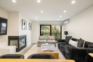 Ein modernes Wohnzimmer mit Kamin, zwei Sofas, einem Couchtisch und einem Fernseher.