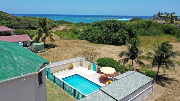 A residential property with a swimming pool, a patio with outdoor furniture, and a view of the ocean. - Entire Villa with Pool, Ocean View & A/C - 5min to beach and Culpepper Spring (St. Philip)